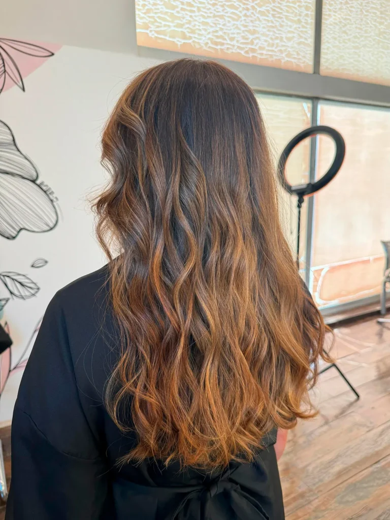 Depois: cabelo castanho com mechas acobreadas e ondas